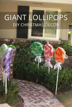 some lollipops are sitting on top of sticks in front of a house