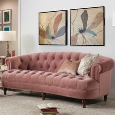 a living room with two paintings on the wall and a pink couch in front of it