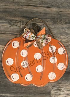 an orange pumpkin with white polka dots and a bow on the top is sitting on a wood floor