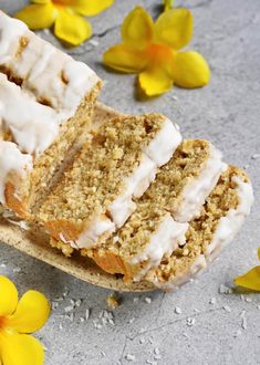 two slices of cake sitting on top of a wooden cutting board next to yellow flowers