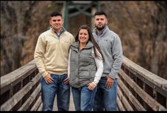 two men and a woman standing on a bridge