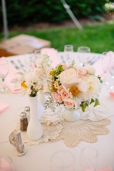 a white vase filled with flowers on top of a table covered in pink napkins