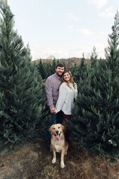 a man and woman standing next to each other with their dog in front of them