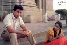 a man and woman sitting on the steps next to each other in front of a building