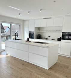 a large kitchen with white cabinets and an island in front of a sliding glass door