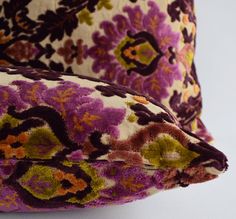 two pillows with different patterns on them sitting next to each other in front of a white background