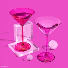 two pink martini glasses sitting next to each other