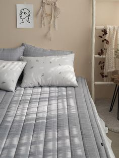 a bed sitting in a bedroom next to a table with two pillows on top of it