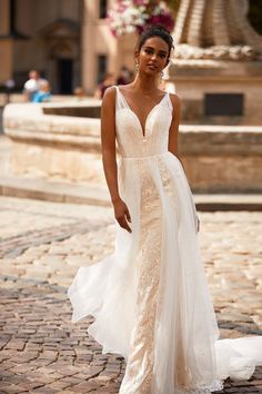 a woman in a wedding dress standing on a cobblestone street with her back to the camera