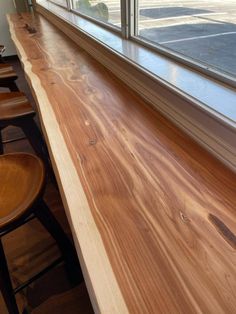 a wooden counter top sitting next to a window in a room with two chairs near by