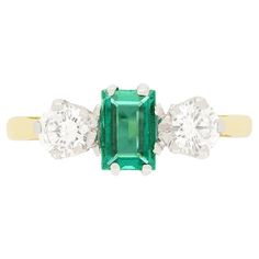 This classic Vintage trilogy ring dates to the 1980s and features a captivating 0.50 carat baguette-cut emerald at its centre, radiating with rich green hues. Flanking the emerald are two round brilliant cut diamonds, each weighing 0.25 carats. Each diamond is of exceptional quality, matching at F in colour and VS1 in clarity. The trio of stones are claw set into platinum collets with a contrasting band of 18 carat yellow gold band completing the ring beautifully. Gemstone: Emerald Stone Shape: Baguette Cut Carat Weight: 0.50 Metal: 18ct White Gold, 18ct Yellow Gold Age: 1980s Size: N Heart Shaped Diamond Ring, Carved Ring, Three Stone Ring, Three Stone Engagement, Heart Shaped Diamond, Stone Engagement Rings, Platinum Ring, Three Stone Rings, Emerald Diamond