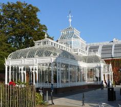 a large white glass house sitting in the middle of a park