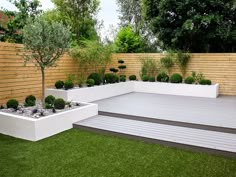 an outdoor garden with white planters and wooden steps leading up to the deck area