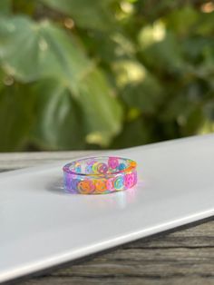 two colorful bracelets sitting on top of a white laptop computer next to a plant