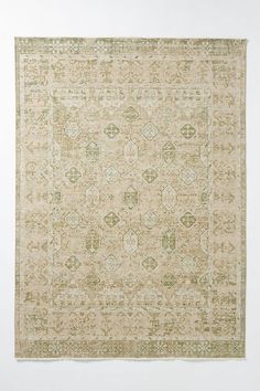 a beige and green rug with an intricate design