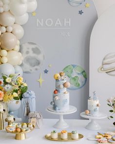 a table topped with cakes and desserts next to balloons in the shape of planets