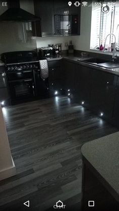 an image of a kitchen setting with lights on the floor and counter tops in black