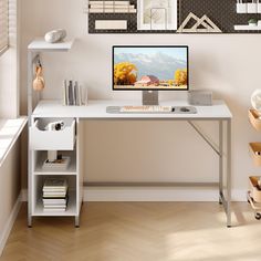 a desk with a computer on it in front of a wall mounted art work area