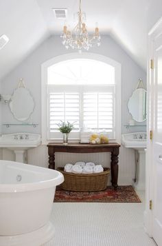 a white bathroom with a tub, sink and mirror in the corner next to two sinks