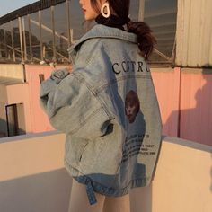 a woman standing on top of a roof with her back to the camera and wearing a jean jacket