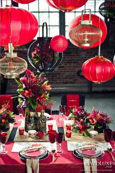 red lanterns hang from the ceiling above a table with place settings and flowers on it