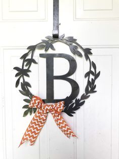 a door hanger with the letter b and an orange bow hanging from it's side