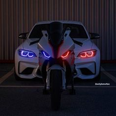 two white sports cars parked next to each other in a parking lot with the lights on