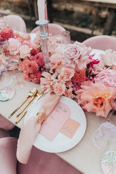 the table is set with pink flowers and gold place settings for an elegant dinner party