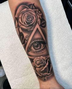 a black and white tattoo with roses, an eye and a triangle on the leg