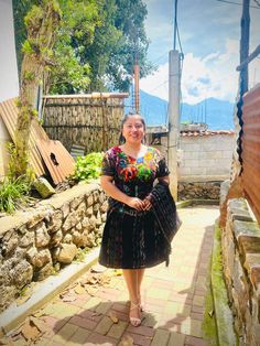 a woman in a colorful dress is walking down the street with her hand on her hip