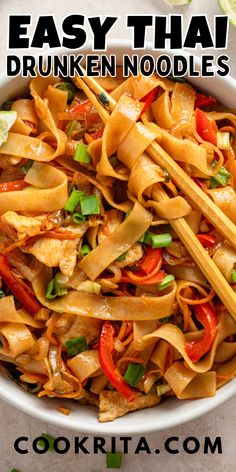 a bowl filled with noodles and vegetables on top of a table next to chopsticks