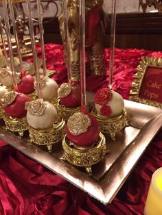 red and white cake pops are on a silver platter with gold trimmings