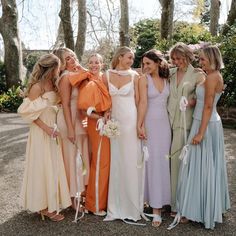 a group of women standing next to each other wearing dresses and holding bouquets in their hands