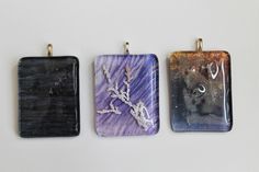 three pendants with different designs on them sitting next to each other in front of a white background