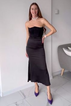 a woman in a black dress posing for the camera with her hands on her hips