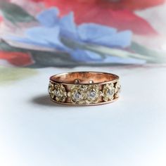 a close up of a wedding ring on a table with flowers in the back ground