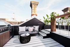 an outdoor living area with couches, tables and grills on the roof terrace