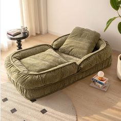 a green couch sitting on top of a wooden floor next to a potted plant