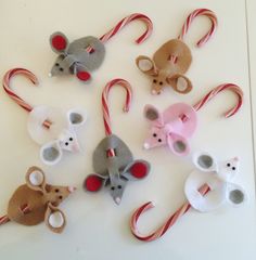 several felt mice and candy canes are arranged on a white surface, with one mouse in the middle