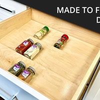 an open drawer with spices and condiments in it, labeled made to fit the refrigerator