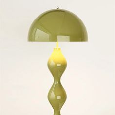 a green lamp sitting on top of a wooden table next to a white wall and floor