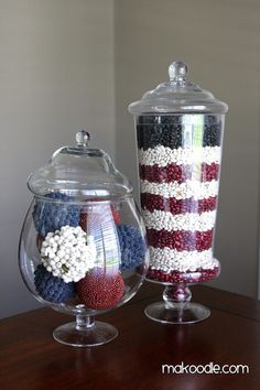 two glass vases with red, white and blue candies in them on a table