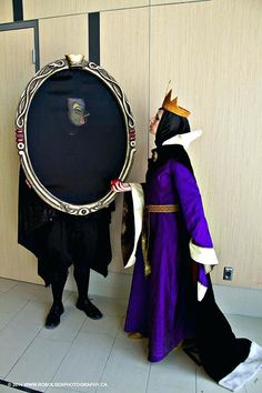 two people dressed up in costumes standing next to each other holding a large round object