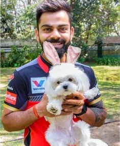 a man holding a small white dog in his hands