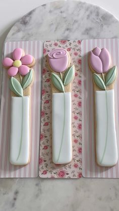 three decorated cookies in the shape of vases with flowers