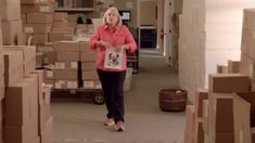 a woman walking through a room filled with boxes