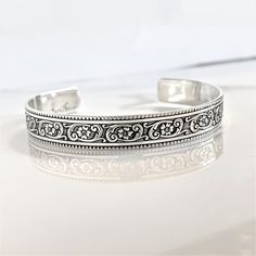 "Details:  - one 3/8\" width solid sterling silver cuff bracelet engraved with a floral motif on the outside - your choice of wording on the inside (175 Characters or less) - your choice of size (6\" is the most common size) - all cuffs can be adjusted with steady pressure to be made tighter or looser ~DON'T FORGET TO GRAB A SUNSHINE POLISHING CLOTH: https://www.etsy.com/listing/469627127/sunshine-cleaning-cloth-for-jewelry?ref=shop_home_active_1 CHECK OUT MY ENTIRE SHOP! https://www.etsy.com/shop/TatumBradleyCo?ref=si_shop" Classic Adjustable Cuff Bracelet With Intricate Design, Stamped Sterling Silver Bangle Cuff Bracelet, Stamped Sterling Silver Cuff Bracelet, Sterling Silver Stamped Cuff Bangle, Silver Stamped Cuff Bracelet For Wedding, Engraved Sterling Silver Cuff Bangle, Adjustable Engraved Silver Cuff Bracelet, Classic Cuff Bracelet With Intricate Design As Gift, Adjustable Etched Cuff Bracelet For Anniversary