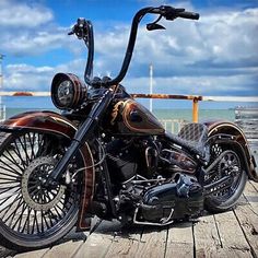 a black and brown motorcycle parked on top of a wooden pier next to the ocean