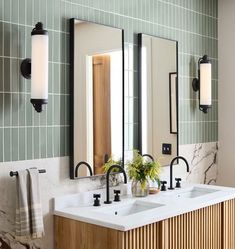 a bathroom with two sinks, mirrors and lights on the wall next to each other