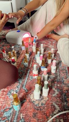 two women are sitting on the floor with many small bottles